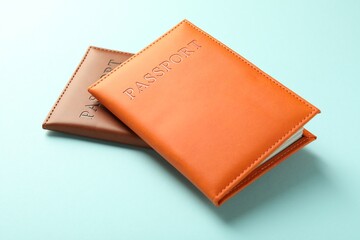 Passports in color covers on light blue background, closeup