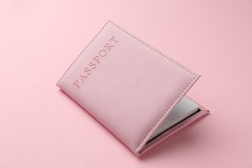 Passport in color cover on pink background, closeup