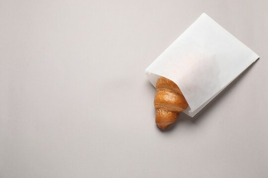 Paper bag with fresh croissant on beige background, top view. Space for text - Powered by Adobe