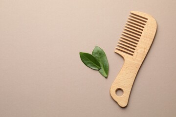 Wooden comb and leaves on beige background, flat lay. Space for text