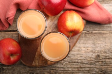 Tasty apple juice in glasses and fresh fruits on wooden table, flat lay