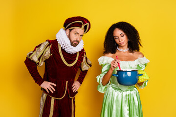 Couple in elegant historical costumes against yellow background, depicting royal fashion and traditional era concepts