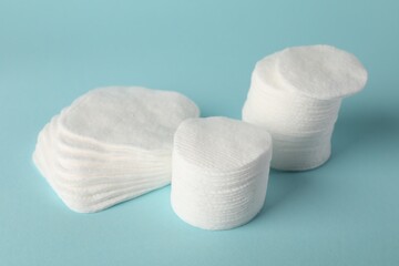 Clean cotton pads on light blue background, closeup