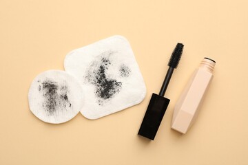 Dirty cotton pads and mascara on beige background, flat lay