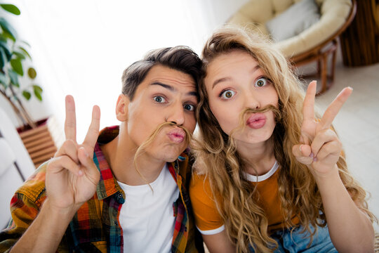Photo of cute young couple fake mustache v-sign cozy day light spring summer home interior living room - Powered by Adobe