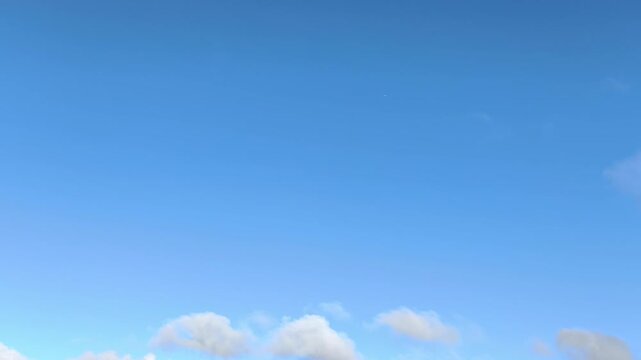 Morning landscape of puffy clouds moving across the clear blue sky