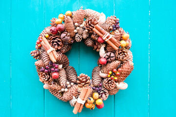 Christmas wreath on a turquoise blue green wooden door. Christmas mood: festive christmasy themed winter natural wreath on a turquoise blue green wooden door. Charming wreath. Christmas decoration.