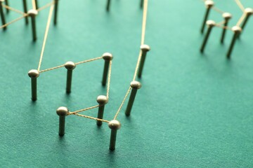 Network connection. Nails linked together by thread on green background, closeup. Space for text