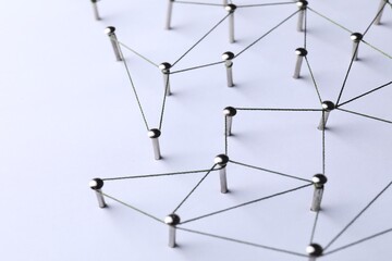 Network connection. Nails linked together by threads on white background, closeup