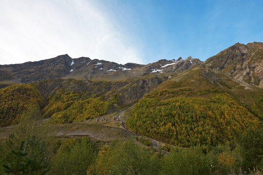 Autumn mountain landscape. A rocky mountain with snow remnants on the top and avalanche protection on the slope. Elbrus region.