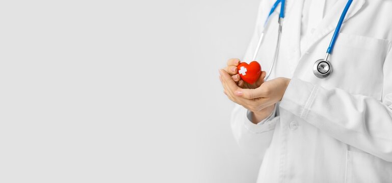 Cardiologist holding red heart on light background with space for text, closeup