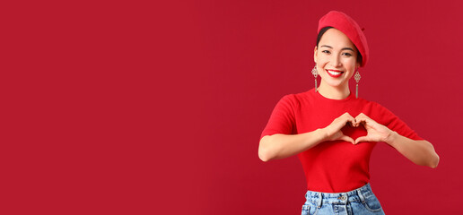 Fashionable Asian woman making heart with her hands on color background