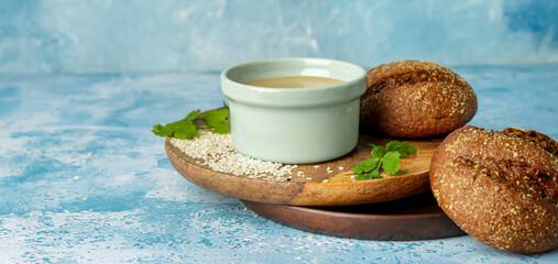 Bowl of tasty tahini with bread on color background