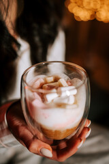 Woman Enjoys Cappuccino With Marshmallows in Cozy Bed Setting Beside a Beautifully Decorated Christmas Tree