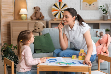 Female speech therapist with little girl pronouncing letter C in office