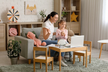 Female speech therapist working with laptop and little girl in office