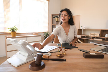 Female African-American lawyer picking up phone at table in office