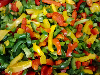 a mixture of colorful peppers, including red, green and yellow bell peppers. A vibrant variety of colors and rich textures, ideal for illustrating frozen foods, healthy eating, or culinary themes.