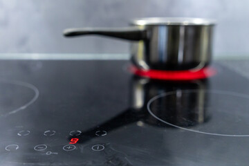 boiling water in a stainless steel pot on an induction stove with red heating light and digital...