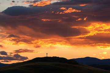 Silhouette of a Cross Against a Dramatic Sunset Sky with Colorful Clouds and Mountains in the Background Highlighting Religious Significance and Natural Beauty