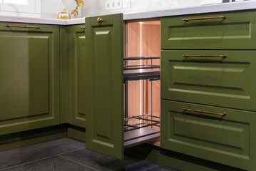 Open drawer in a green kitchen cabinet