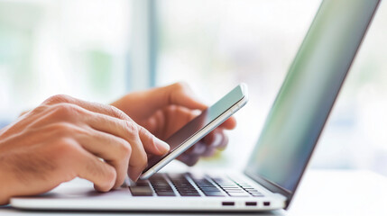 Hands working on a laptop with a smartphone nearby, showcasing a tech-driven approach to modern work and multitasking hands, laptop, smartphone, workspace, technology, multitasking