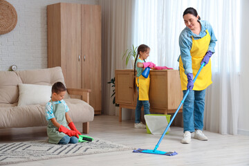 Cute little children helping their mother with cleaning routine at home