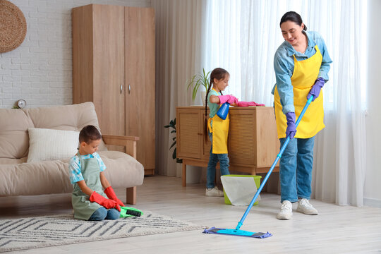 Cute little children helping their mother with cleaning routine at home