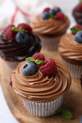 Tasty cupcakes with chocolate cream and berries on white table, closeup