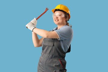 Young female mechanic with crowbar on blue background. Woman in male profession concept
