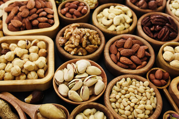 Colorful mix of various nuts: peanut and cashew, hazelnut and almond, pine nuts and walnut; healthy diet snack; vegan food background, selective focus, shallow focus