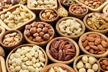 Colorful mix of various nuts: peanut and cashew, hazelnut and almond, pine nuts and walnut; healthy diet snack; vegan food background, selective focus, shallow focus