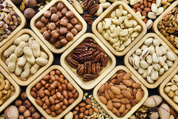 Colorful mix of various nuts: peanut and cashew, hazelnut and almond, pine nuts and walnut; healthy diet snack; vegan food background, selective focus, shallow focus
