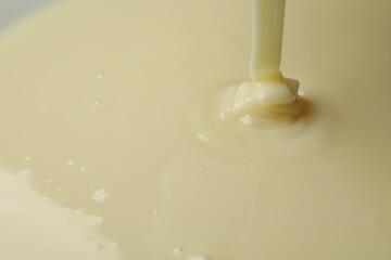 Pouring delicious condensed milk as background, closeup