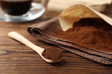 Paper filter and ground coffee on wooden table, closeup