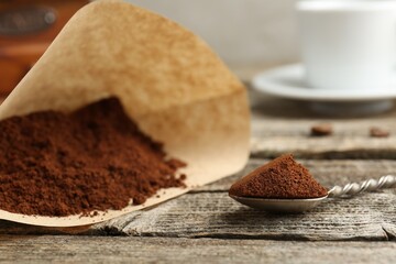 Paper filter and ground coffee on wooden table, closeup