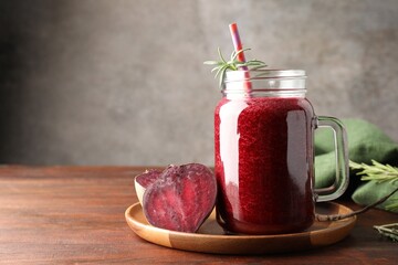 Fresh beetroot smoothie in mason jar and vegetables on wooden table, closeup. Space for text