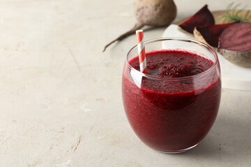 Fresh beetroot smoothie in glass on grey textured table, closeup. Space for text
