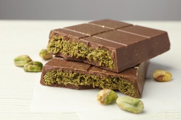 Pieces of tasty Dubai chocolate with pistachios and knafeh on white wooden table, closeup
