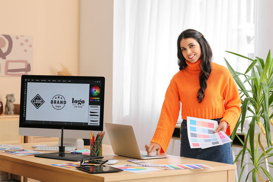 Young female graphic designer working with color palettes and laptop in office