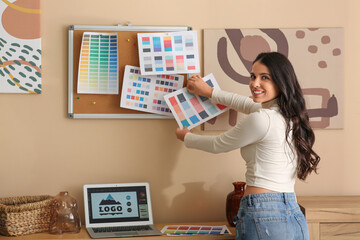 Young female graphic designer pinning color palette on cork board in office