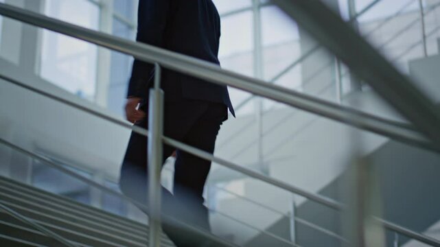 Ambitious manager climbing stairs modern office back view. Businessman walking 