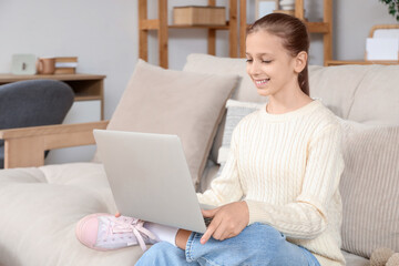 Teenage girl using laptop on sofa at home