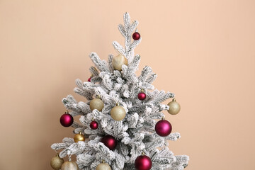 Christmas tree with decorations near beige wall in room. Closeup