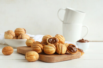 Cutting board of sweet walnut shaped cookies with boiled condensed milk on white wooden table