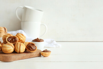 Cutting board of sweet walnut shaped cookies with boiled condensed milk on white wooden table