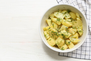 Bowl of tasty potato salad with dill on white wooden background