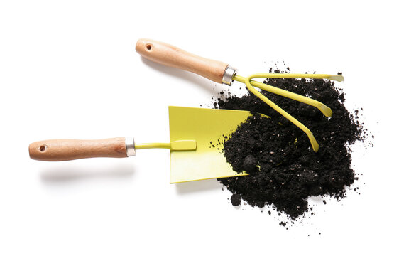 Heap of soil, gardening shovel and rake on white background