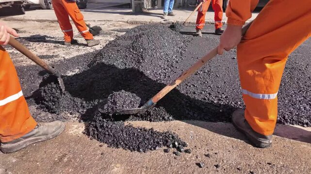 Construction workers working on a new asphalt layer on a public street.	
