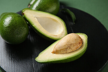 Black board with fresh ripe avocados on green background, closeup